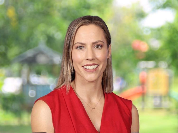 Nerida Clift wearing red sleeveless top in front of blurred school playground