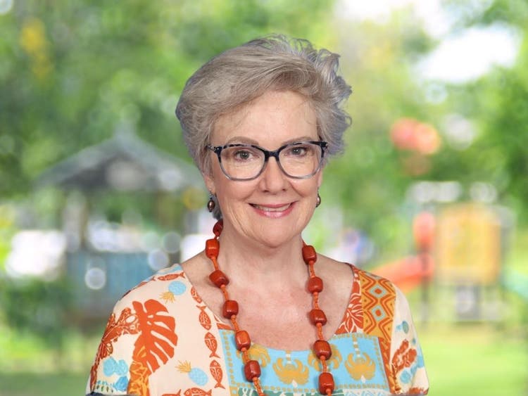 Tracey Stevenson wearing orange and teal patterned top in front of blurred school playground