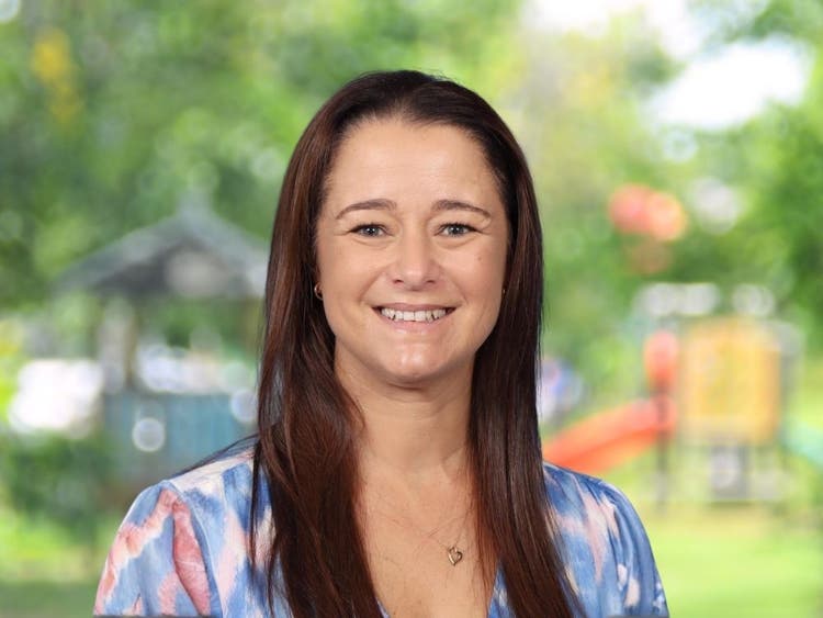 Yvonne Tremlett wearing pastel purple and pink top in front of blurred school playground