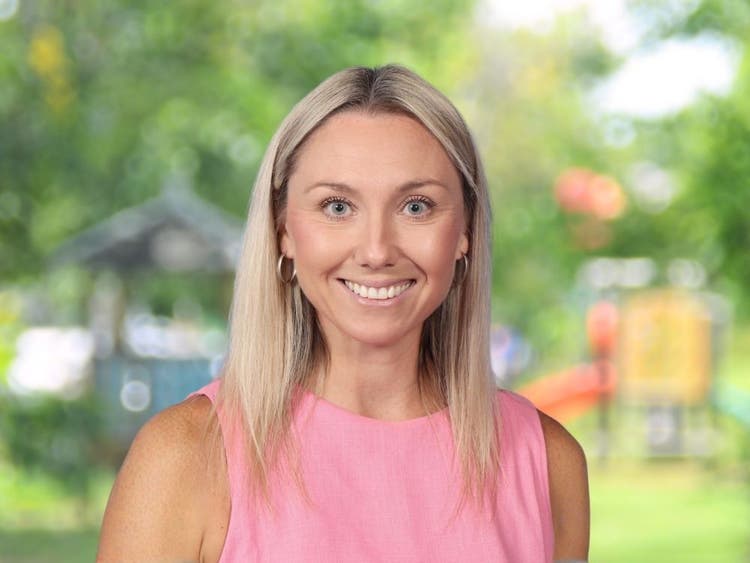 Kristy Abbott wearing pink top in front of blurred school playground