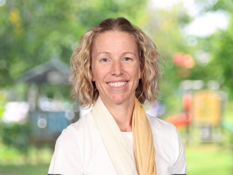 Gaynor Long wearing white top with two-toned yellow scarf in front of blurred school playground